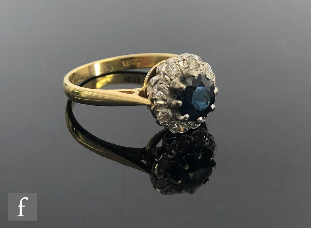 An 18ct sapphire and diamond cluster ring, central circular sapphire within a border of eight