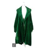 A 1920s vintage opera coat in emerald green velvet with a deep ruched collar and bell sleeves,