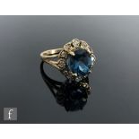 A 9ct hallmarked London blue topaz and diamond cluster ring, central oval claw set topaz within a