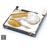 A cased hallmarked silver back three piece brush set with part embossed foliate decoration,