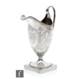 A George III silver cream jug of helmet form, with reeded rim and loop handle, engraved with foliate