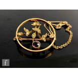 An Edwardian 15ct circular open work brooch modelled as an amethyst and seed pearl spray within