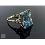 A 9ct hallmarked blue topaz and diamond ring, central emerald cut topaz, length 16.5mm, flanked by