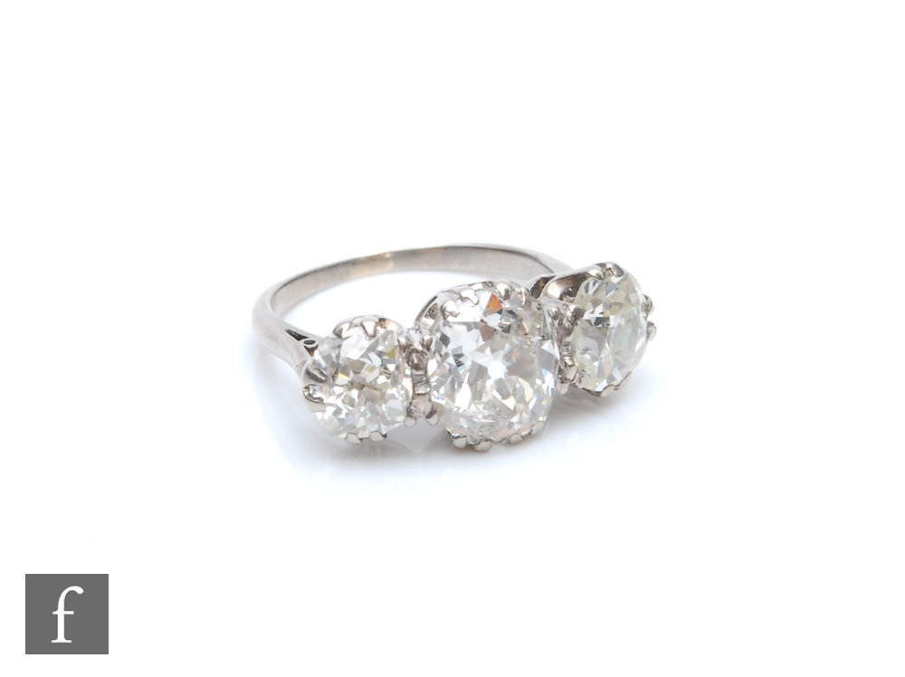 An early 20th Century platinum diamond three stone ring, old cut claw set stones, centre stone