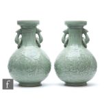 A pair of Chinese celadon vases, each of bottle form rising to a dish-mouth rim, applied with