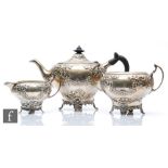 A hallmarked silver three piece tea set of oval pedestal form with part foliate embossed decoration,