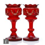 A pair of late Victorian ruby glass table lustres with wide circular foot rising to a knopped stem