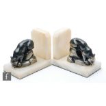 A pair of 20th Century Art Deco bookends, decorated with silvered spelter stylised panthers on rocky