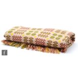 A vintage Welsh woollen blanket with traditional repeat pattern in green, yellow and brown against a