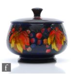 William Moorcroft - A small bowl and cover decorated in the Flambe Leaf and Berry pattern, impressed