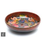 William Moorcroft - A shallow bowl decorated in the Flambe Frilled Orchid pattern, impressed