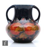 William Moorcroft - A twin handled vase decorated in the Pomegranate pattern with a band of whole