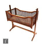 A late 19th and early 20th Century chequer strung mahogany bergere crib on trestle frame, height