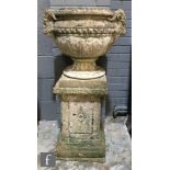 A 20th Century composite stone pedestal two handled ram's head urn on square base, height 86cm.