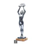 A chrome Art Deco figure of a scantily clad female figure, with arms raised holding a basket of