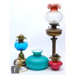 A 20th Century brass oil lamp and shade, another with blue reservoir and one other with chimneys,