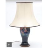 A Moorcroft table lamp decorated in the Clematis pattern with tubed flowers against a green blue