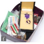A collection of military badges and cloth patches, a cased Purple Heart, also medals awarded to