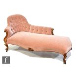 A Victorian carved walnut chaise longue upholstered in pale pink buttoned back plush, on carved legs