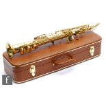 A British made Warwick brass saxophone with attachments in plush lined carrying case, width 61cm.