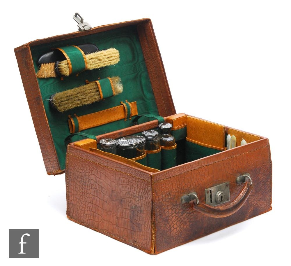 An Edwardian lady's dressing case fitted with four silver topped bottles, three brushes and other