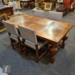 An early 20th Century oak draw-leaf refectory style dining table with marquetry top, raised to