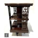An Edwardian inlaid mahogany revolving bookcase, the shaped fan decorated top over pierced slatted