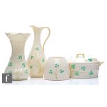 Four pieces of Belleek comprising a butter box and cover formed as a barrel, a spill vase, a jug and