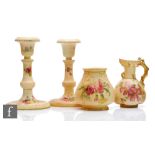 A pair of Royal Worcester blush ivory candlesticks decorated with sprays of flowers, puce mark