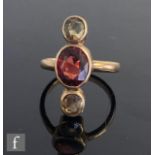 An early 20th Century 9ct garnet and citrene three stone ring, central oval garnet flanked above and