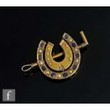 A late 19th Century 15ct brooch modelled as a double horse shoe and riding crop set with alternating