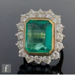 An 18ct hallmarked emerald and diamond cluster ring, central emerald cut, collar set emerald, weight