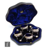 A cased set of four hallmarked silver circular open salts, each raised on four pad feet and