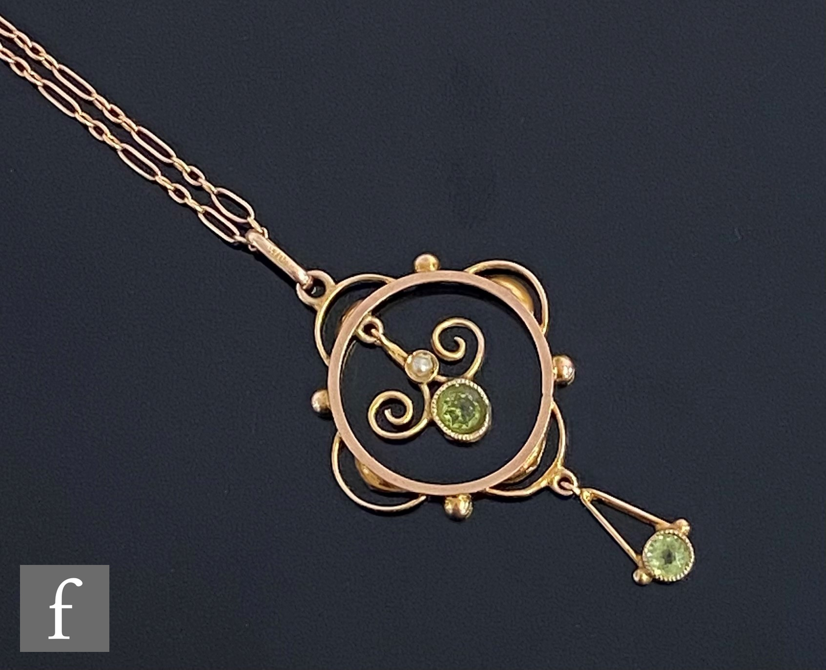 An early 20th Century 9ct two stone peridot open work pendant, suspended from a fetter link chain,