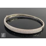 A modern 18ct white gold pave set diamond hinged bangle comprising five rows of brilliant cut