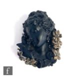A 19th Century black glass and bronze brooch, head and shoulder portrait of a young woman with a