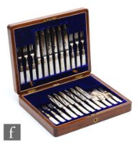 A cased set of twelve mother of pearl handled fruit knives and forks each with engraved foliate