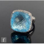 A 14ct white gold blue topaz and diamond ring, central domed facet cut cushioned square topaz within