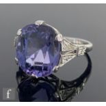 An 18ct white gold natural violet spinel and diamond ring, central claw set oval spinel weight