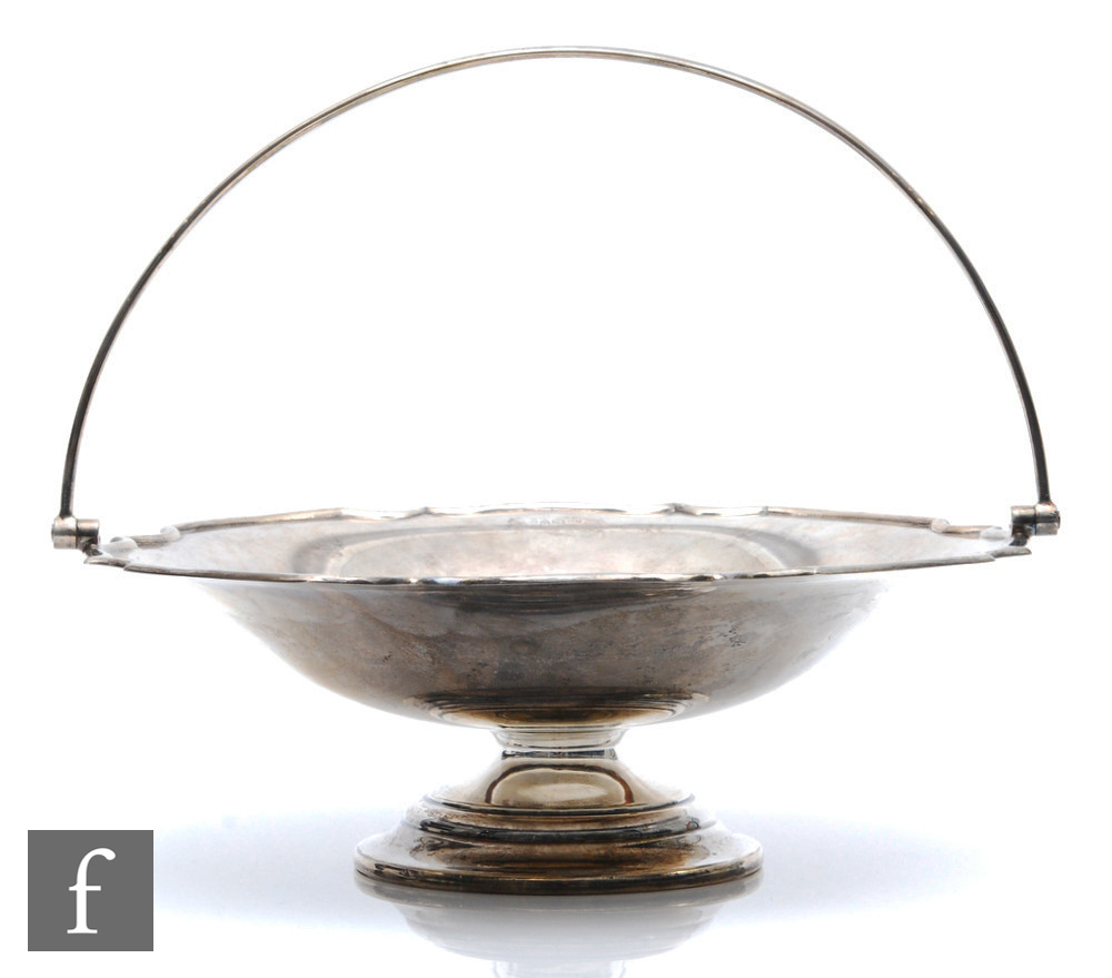 A hallmarked silver pedestal swing basket, circular stepped base below plain bowl and arched swing