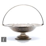 A hallmarked silver pedestal swing basket, circular stepped base below plain bowl and arched swing