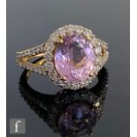An 18ct hallmarked kunzite and diamond cluster ring, central oval kunzite weight 5.5ct, within a