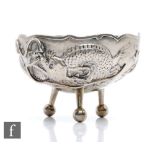 An early 20th Century Chinese silver circular bowl decorated with a scrolling dragon and raised on