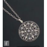 A modern 14ct white gold pierced circular pendant set with black and white diamonds to a floral