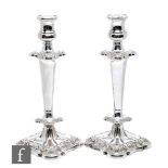 A pair of hallmarked silver candlesticks, foliate embossed shaped square bases below lower knop,
