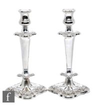 A pair of hallmarked silver candlesticks, foliate embossed shaped square bases below lower knop,