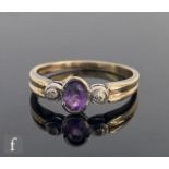 A 9ct hallmarked amethyst and diamond three stone ring, central oval amethyst flanked by diamonds to