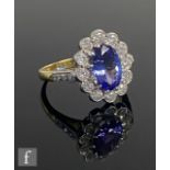 An 18ct tanzanite and diamond cluster ring, central oval tanzanite, length 11mm, within a twelve