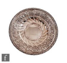A hallmarked silver shallow bowl with central plain well within panelled section rising to foliate