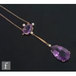 An early 20th Century 9ct two stone amethyst and seed pearl pendant, pear shaped amethyst drop below